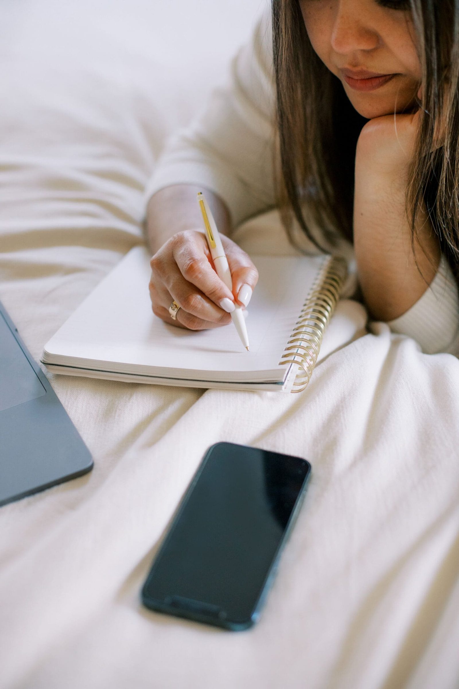 A laptop, phone and notebook open for an online health practitioner to plan strategies for how to generate cash flow in your online practice.