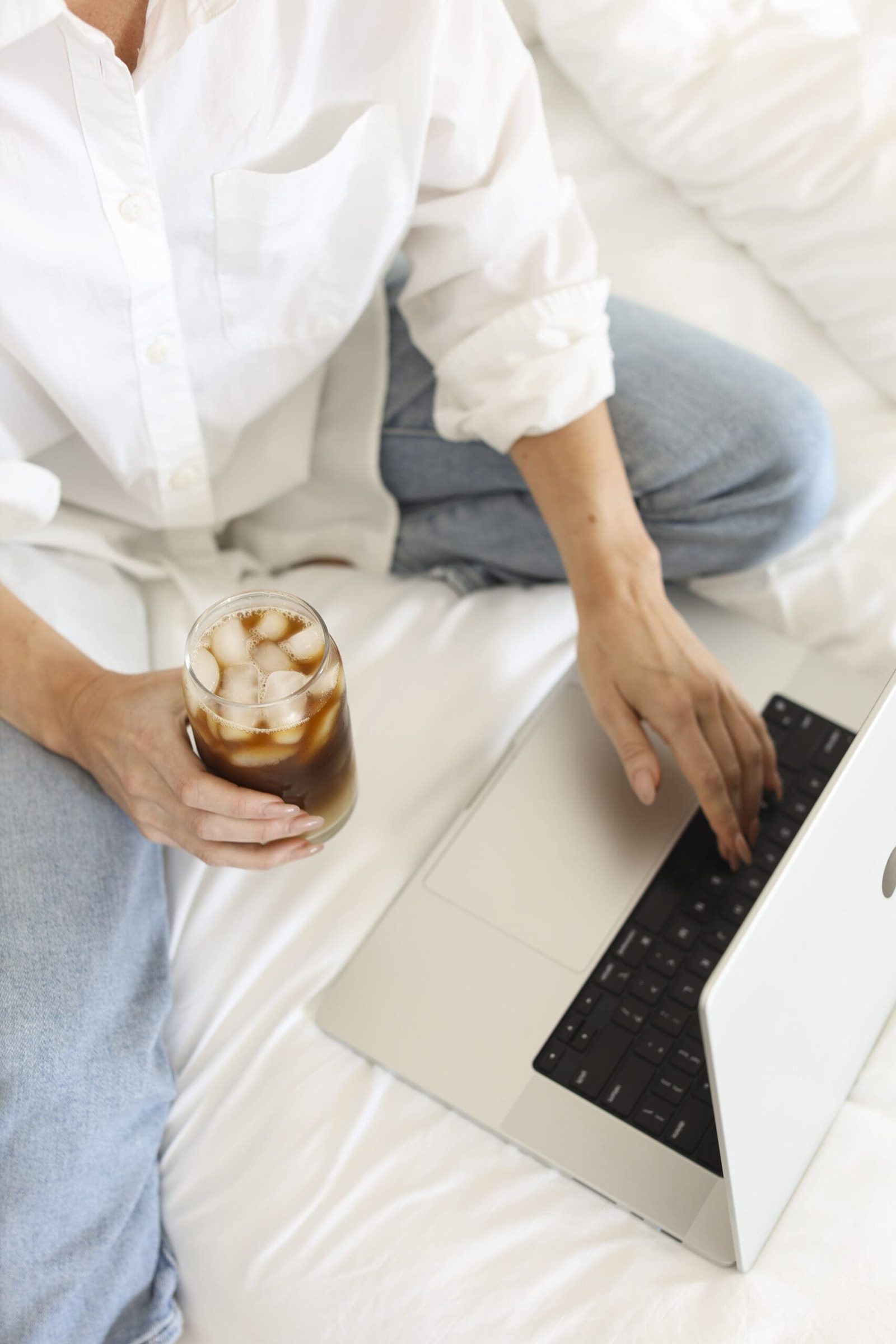 A woman with a drink and laptop searching how to leave insurance as a healthcare practitioner