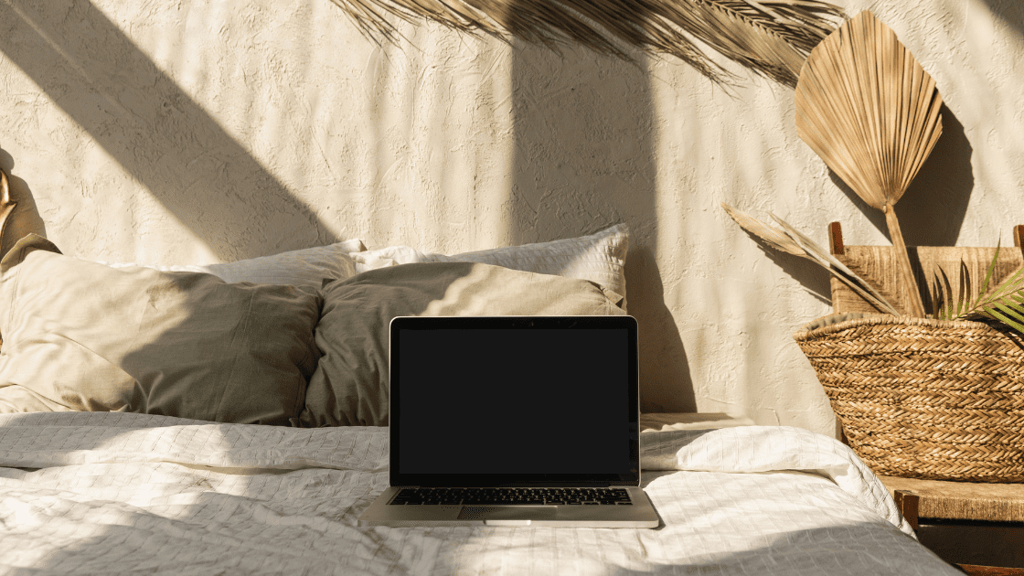 Laptop on cozy bed workspace for online health practitioners attracting clients with clear messaging