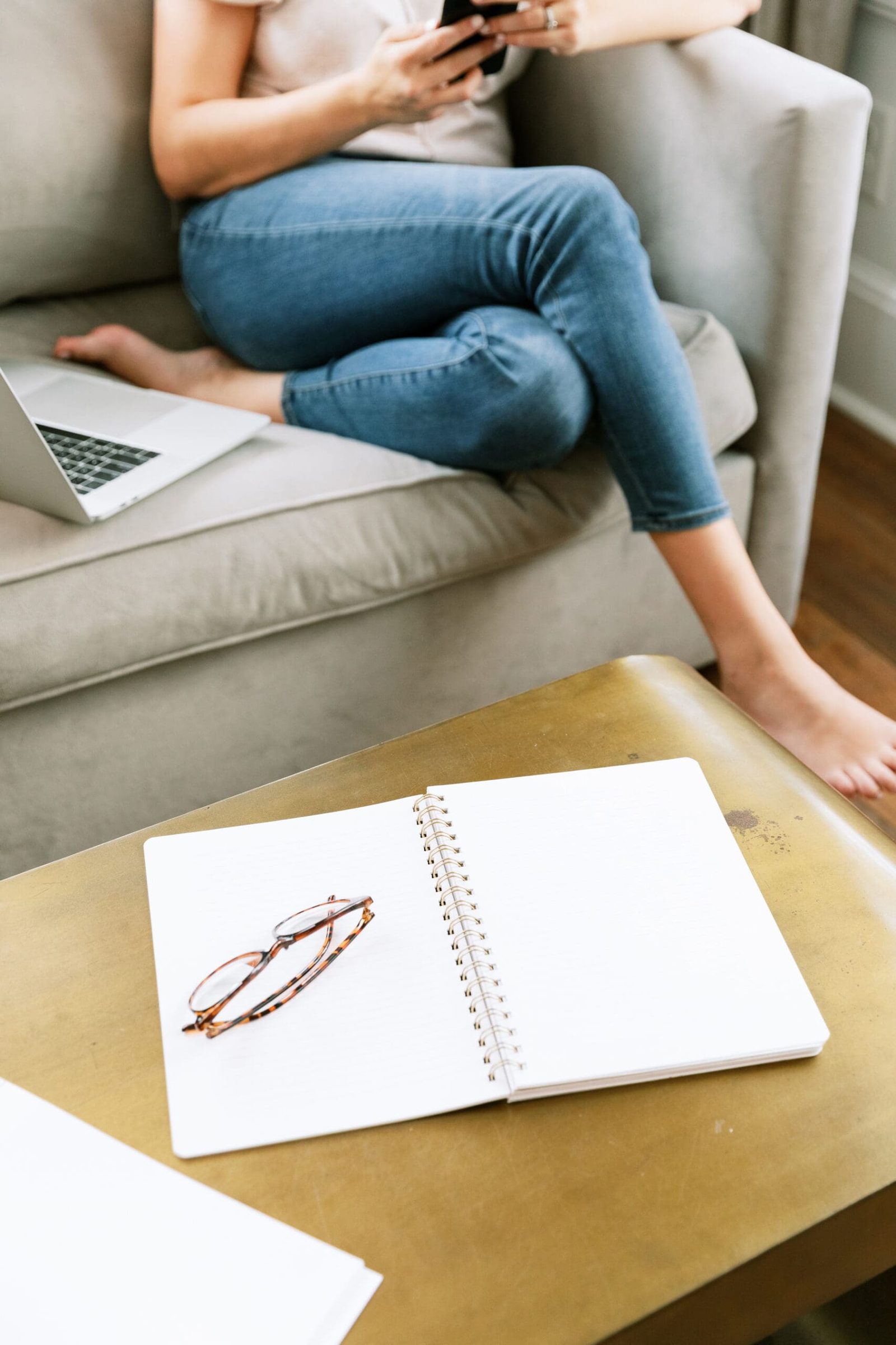 woman sitting on the couch with her laptop and phone learning how to grow an online health practice
