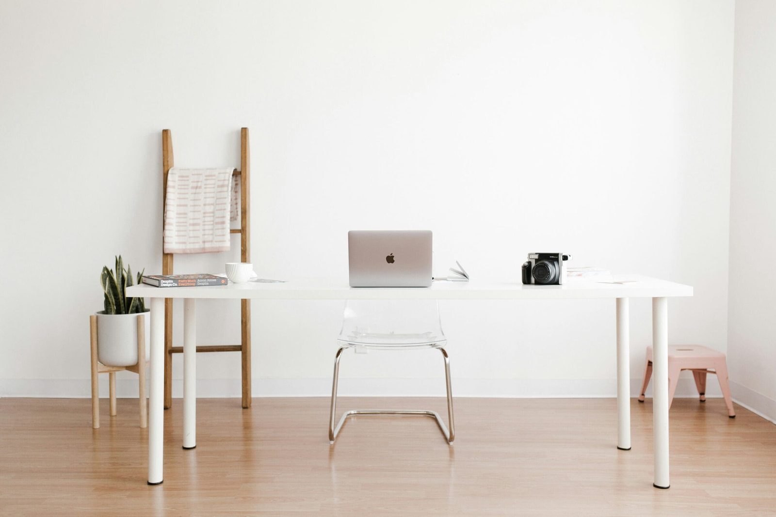 Minimalist home office setup with MacBook, camera, and coffee cup on white desk – clean workspace inspiration.