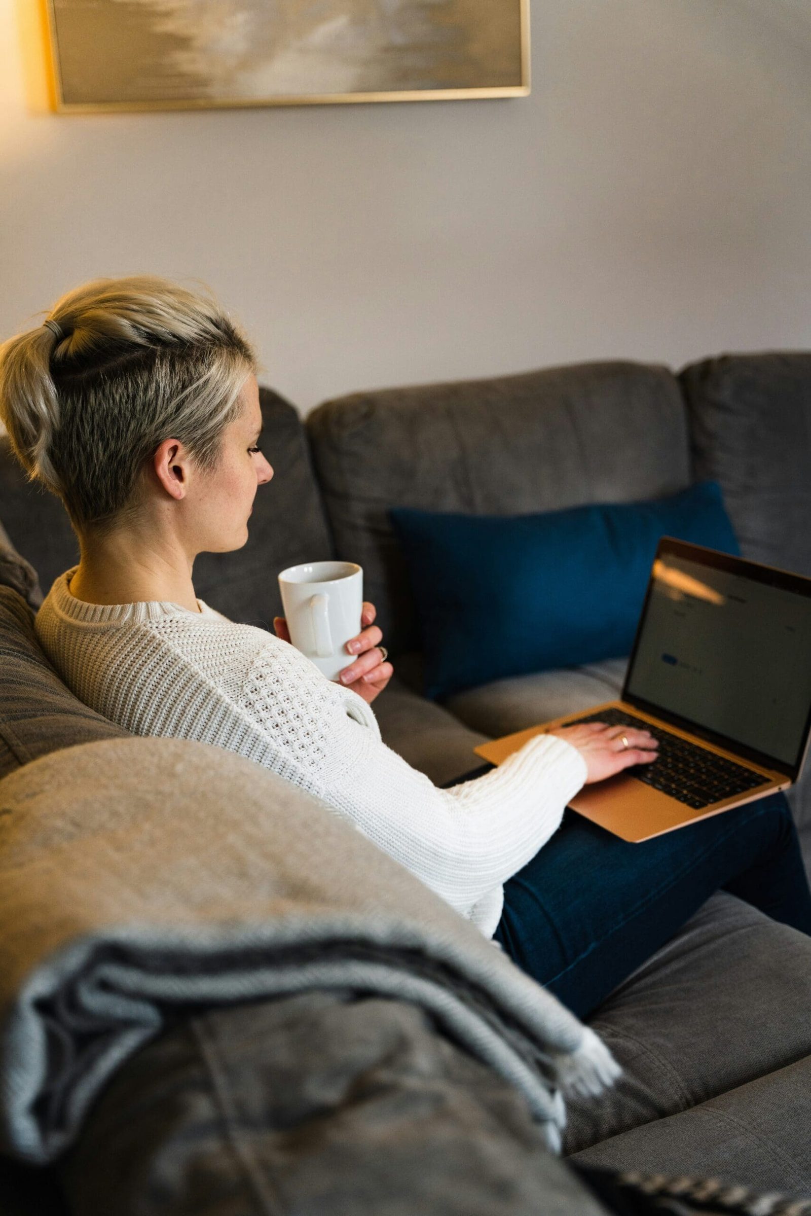 Entrepreneur working remotely from a cozy living room sofa with coffee and laptop – comfortable work-from-home lifestyle.