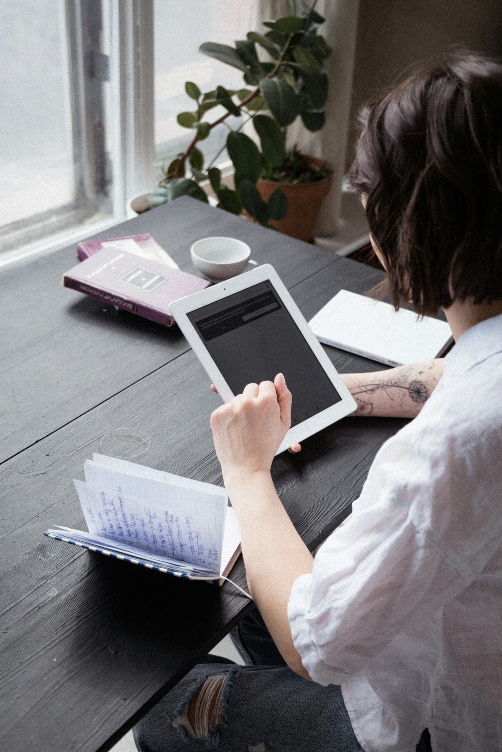 Woman working on a tablet from home, representing the freedom and flexibility of running a virtual health practice.