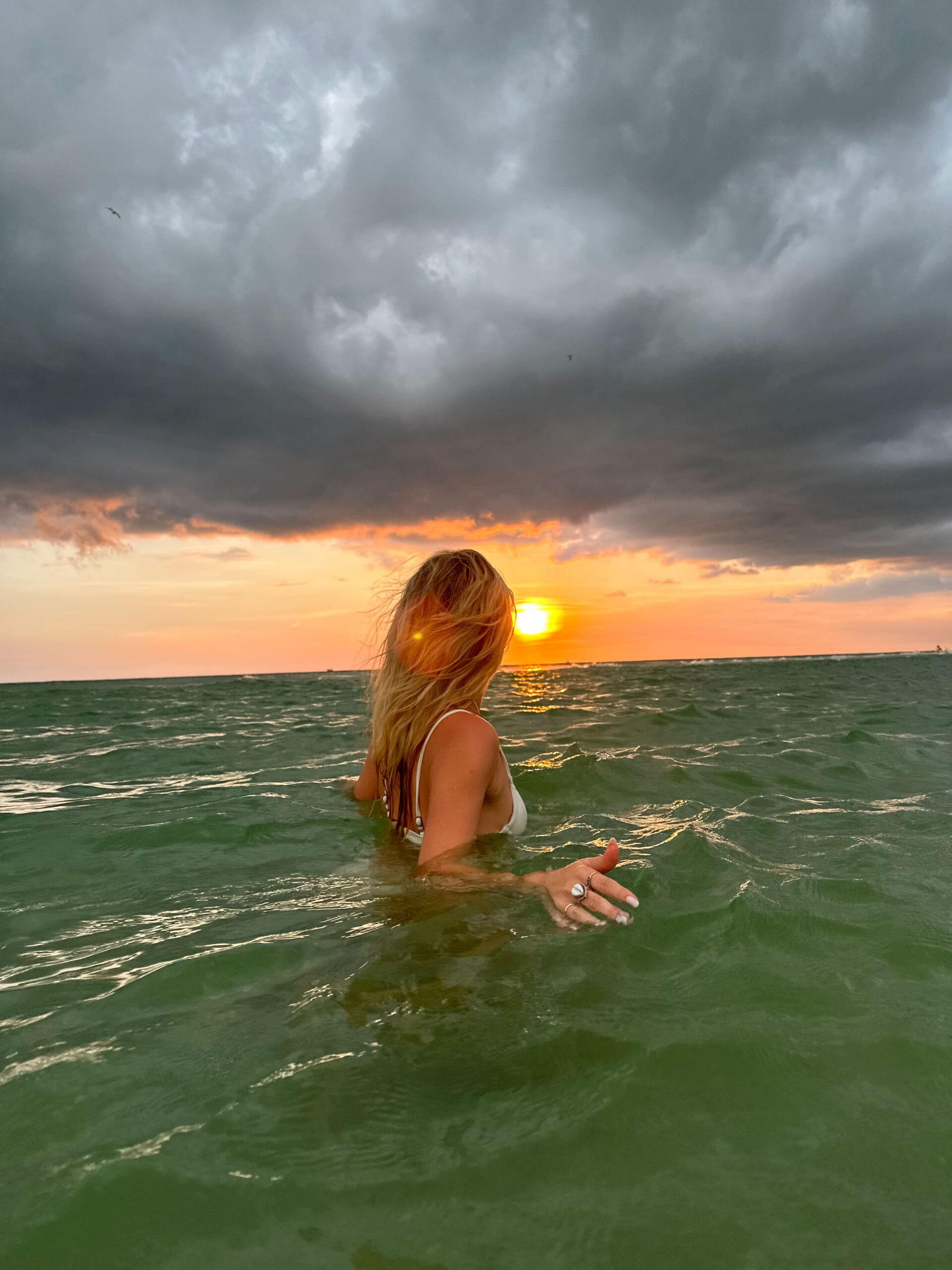 Woman standing in the ocean symbolizing burnout recovery for healthcare practitioners and the transition into a calmer practice in 2026