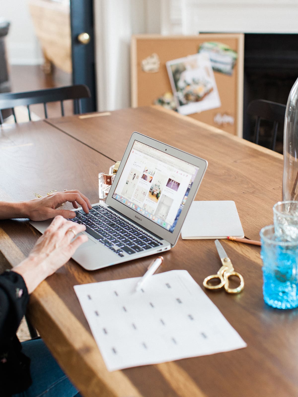an online health practitioner sitting at a desk with her laptop and notebook working on a project after learning how to stop procrastinating